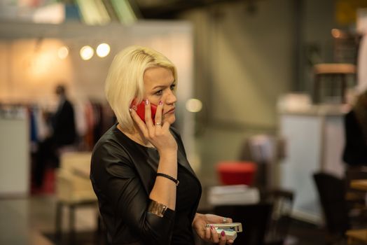 Woman speaking on her phone attending an event at the convention trade center in Brno. BVV Brno Exhibition center. Czech Republic