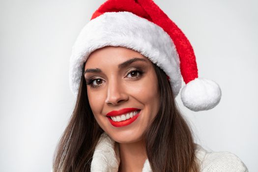 Close up portrait beautifiul caucasian woman in red Santa hat on white studio background. Christmas New Year holiday concept. Cute girl teeth smiling positive emotions with free copy space