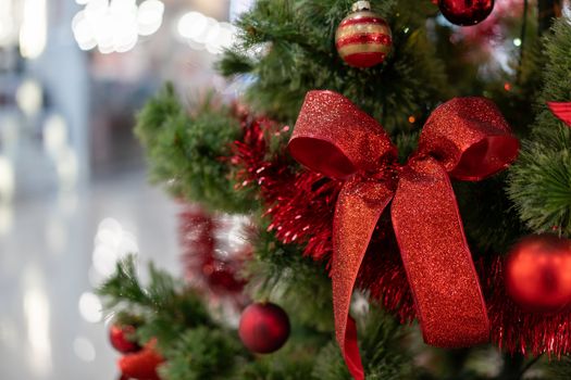 Close Christmas tree in a shopping center against the background of blurry shop windows. Free space for text