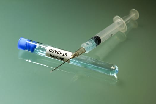Syringe next to test tube with vaccine for Covid-19 virus