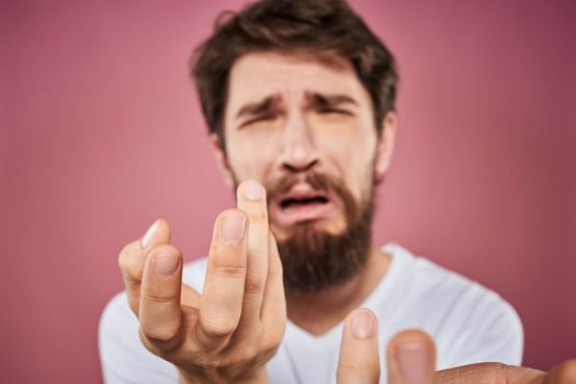 bearded man in white t-shirt emotions displeased facial expression studio pink background. High quality photo