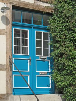 Blue, white painted wooden door with window pane and fanlight in Mecklenburg-Western Pomerania, Germany.