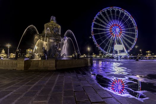 Fountain and Ferris wheel on Concorde square in Paris by night