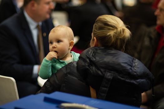 Beautiful small child with her mother while attending an event at the convention trade center in Brno. BVV Brno Exhibition