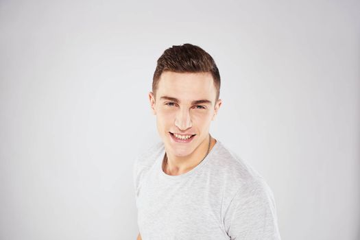 Man in a white t-shirt emotions gestures with hands close-up cropped view light background. High quality photo