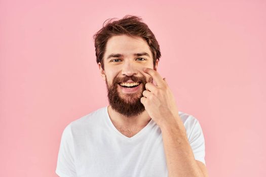 Man in white t-shirt gestures with hands emotions lifestyle cropped view pink background. High quality photo