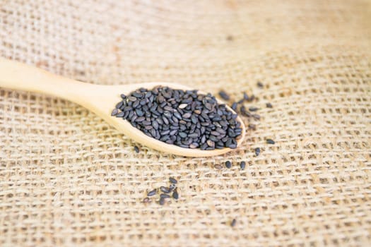 Black sesame seeds in wooden spoon pile 