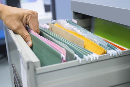 Hand of Man Search files document in a file cabinet in work office, concept business office life.