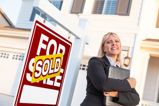 Female Real Estate Agent in Front of Sold For Sale Sign and Beautiful House.