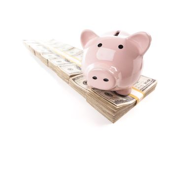 Pink Piggy Bank on Row of Hundreds of Dollars Stacks Isolated on a White Background.