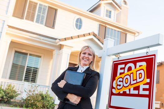 Female Real Estate Agent in Front of Sold For Sale Sign and Beautiful House.
