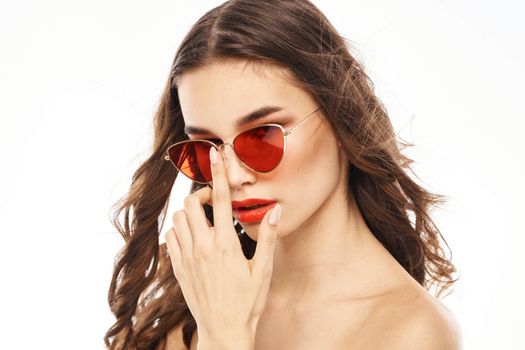 Portrait of brunette woman in sunglasses naked shoulders light background. High quality photo