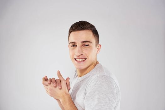 Man in a white t-shirt emotions gestures with hands close-up cropped view light background. High quality photo