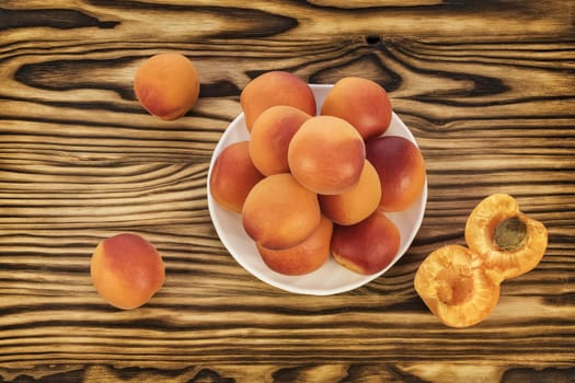 Ripe fresh apricots lie on a table and on a white saucer