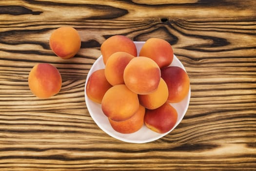 On the table and on a white saucer lie ripe apricots