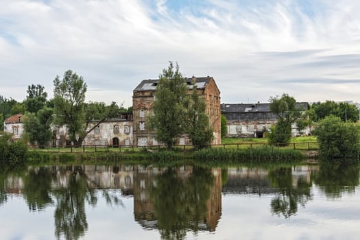 Belarus, Minsk - 08.07.2017: On the river bank there is an old abandoned brick building and is reflected in the water surface