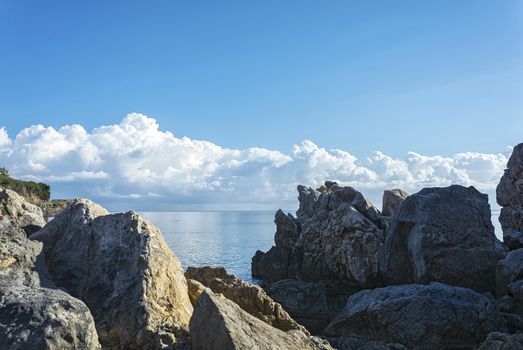 Large coastal stones against the background of the horizon and cumulus clouds