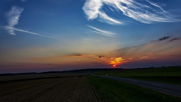 Sunset in the field and the highway leading to the distance