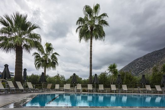 Outdoor swimming pool with sunbeds and umbrellas in cloudy weather