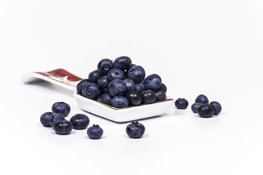 Spoon with large blueberry berries lie on a light background