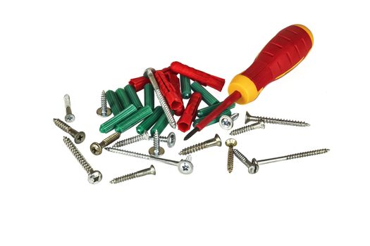 Screwdriver, screws and plastic dowels on a light background
