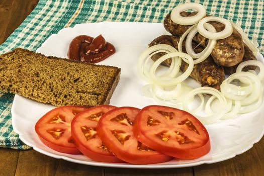 Rural food. Meat sausages with tomato, onion, sauce and bread