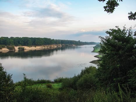 Summer landscape. River with trees along the banks flowing into the distance beyond the horizon                           