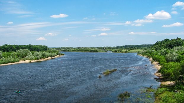 Summer landscape. River with trees on the banks flowing beyond the horizon          