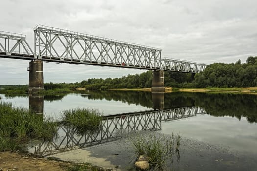 Over the river bed on the concrete supports there is a railway bridge