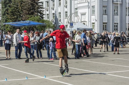 Belarus, Minsk - 27.05.2017: A young man in a red T-shirt and shorts is riding roller skates
