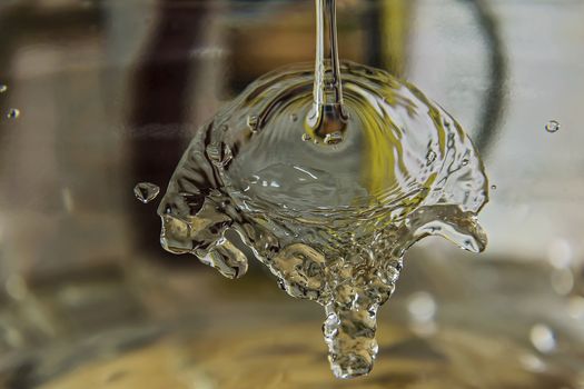 A stream of water splits about a transparent surface and flows down