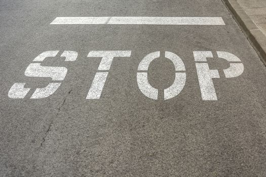 On the roadway of the road there is a sign "STOP"
