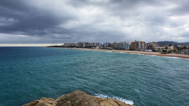 Sandy beach and embankment of the city of Blanes in cloudy weather (Spain)