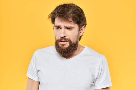 Bearded man emotions gestures with hands facial expression white t-shirt yellow background. High quality photo