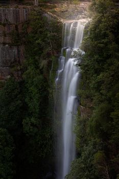 Waterfall drops over high cliff ledge in Southern Highlands from the Yarrunga Creek.  long exposure