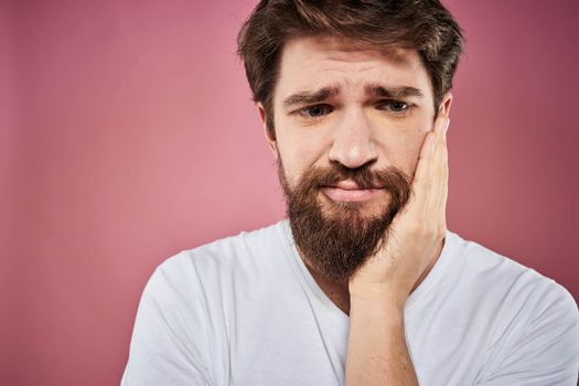 bearded man in white t-shirt emotions displeased facial expression studio pink background. High quality photo