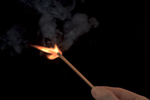 Hand holding a lighted match with fire flame and smoke on a black background.