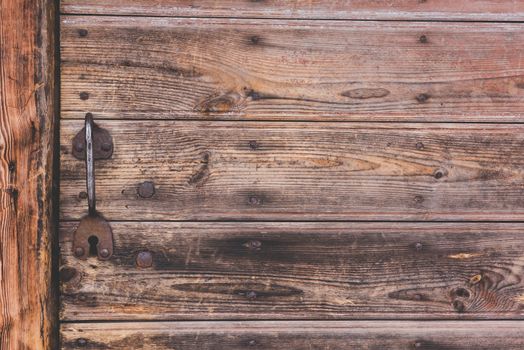 Old metal door handle knocker on a rough wooden background