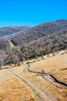 Mountain bikers descend down Thredbo on a cool autumn day in the Snowy Mountains, New South Wales, Australia