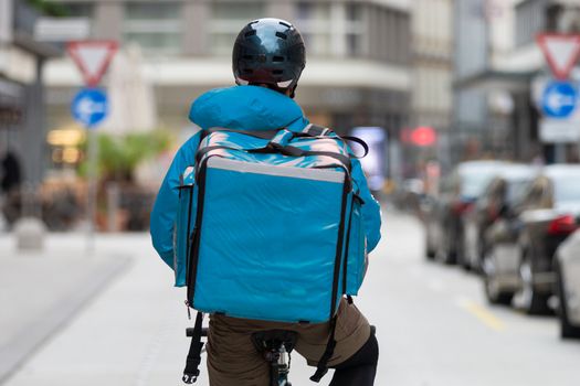 Unrecognizable courier on bicycle delivering food in cCity. Empty streets during shelter in place times during corona virus pandemic, 2020.