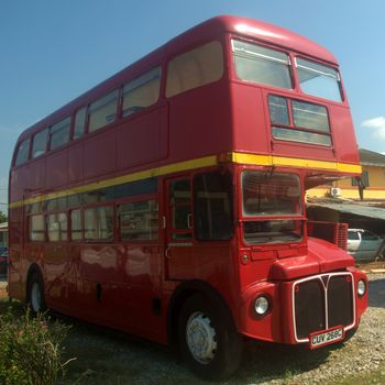 an old model double decker red bus parked in front of a house in Port Dickson Malaysia