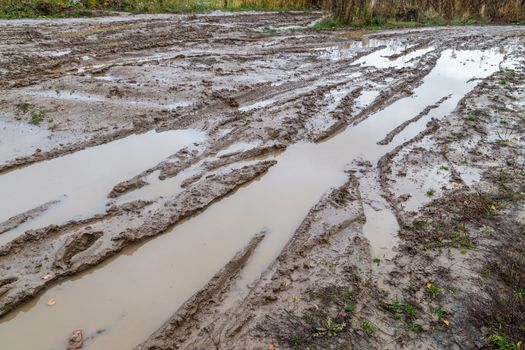 dirty clay mud road with tire tracks - closeup with selective focus and field blur