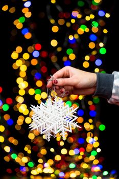 Woman's hands hold christmas decoration. Christmas and New Year holidays background, winter season with Christmas ornaments and blurred lights