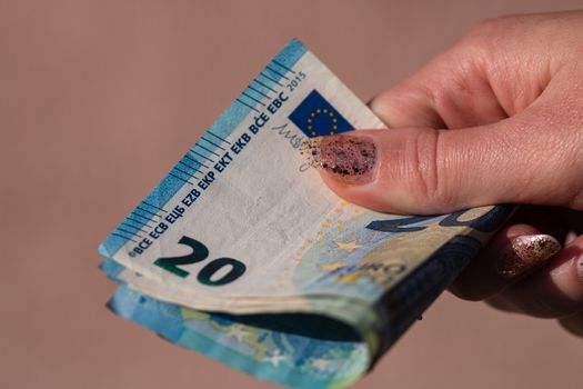 woman hands giving money like a bribe or tips. Holding EURO banknotes on a blurred background, EU currency