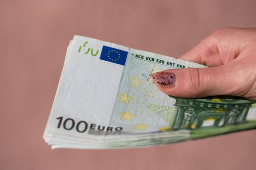 woman hands giving money like a bribe or tips. Holding EURO banknotes on a blurred background, EU currency