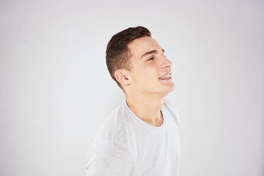 Man in a white t-shirt emotions gestures with hands close-up cropped view light background. High quality photo