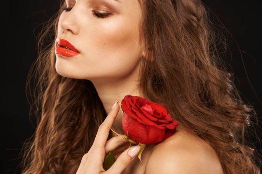 woman with a red rose on a dark background long hair makeup red lips. High quality photo