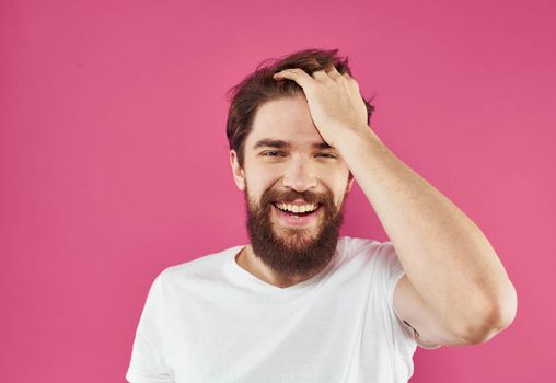 Happy man holds his hands near his face and laughs on a pink background. High quality photo