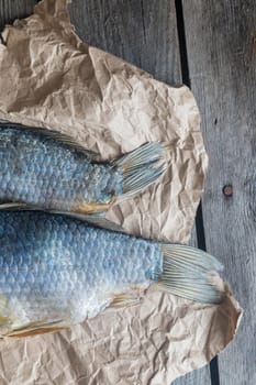 .Tails of Salted Dry fish vobla on crumpled craft paper on wooden background, delicious beer snack, close-up.