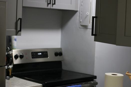 Modern gray kitchen features dark gray flat front cabinets paired with white quartz countertops and a glossy gray linear tile backsplash. Northwest, USA. High quality photo